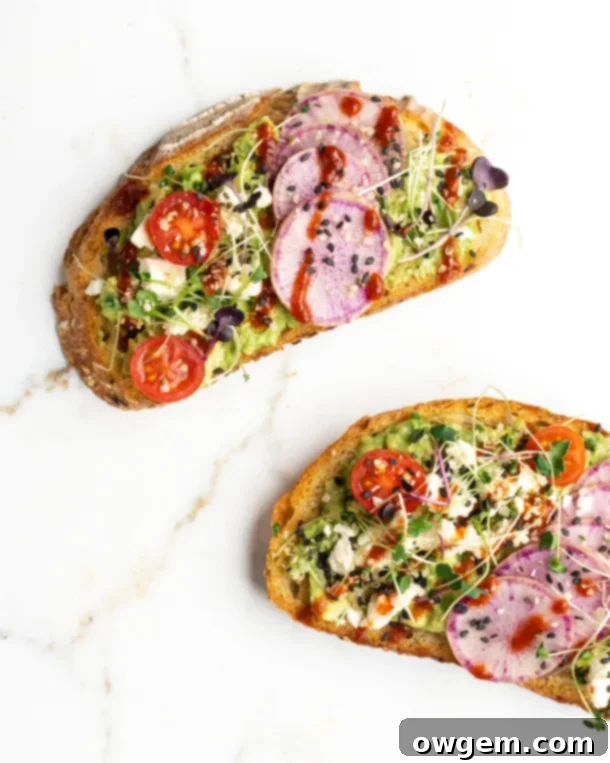 Close-up shot of avocado toast with feta, sriracha, tomatoes, and radishes, ready to eat.
